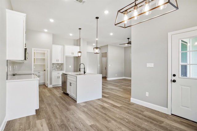 kitchen featuring decorative light fixtures, dishwasher, light hardwood / wood-style floors, white cabinetry, and an island with sink