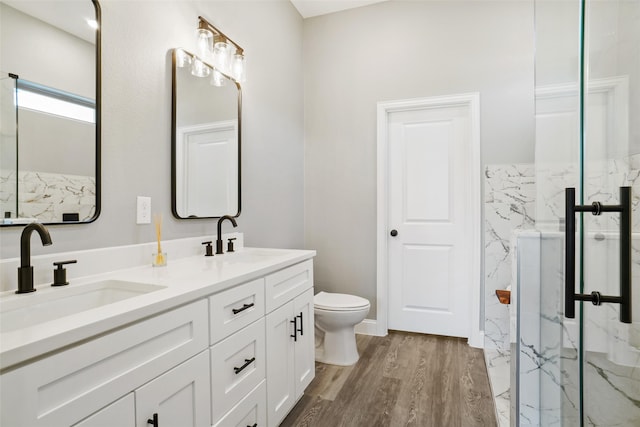 bathroom featuring hardwood / wood-style floors, vanity, a shower with shower door, and toilet