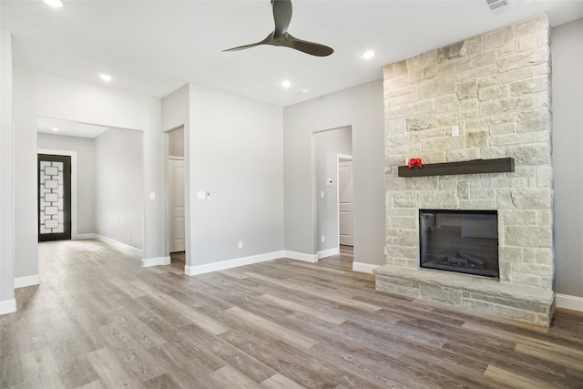 unfurnished living room with a fireplace, light wood-type flooring, and ceiling fan