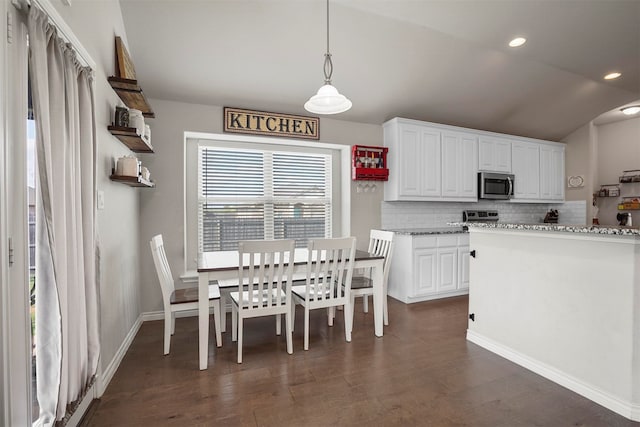 kitchen featuring white cabinetry, hanging light fixtures, dark hardwood / wood-style flooring, lofted ceiling, and appliances with stainless steel finishes