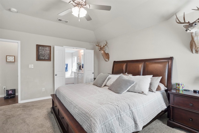 bedroom featuring ensuite bath, ceiling fan, light colored carpet, and vaulted ceiling