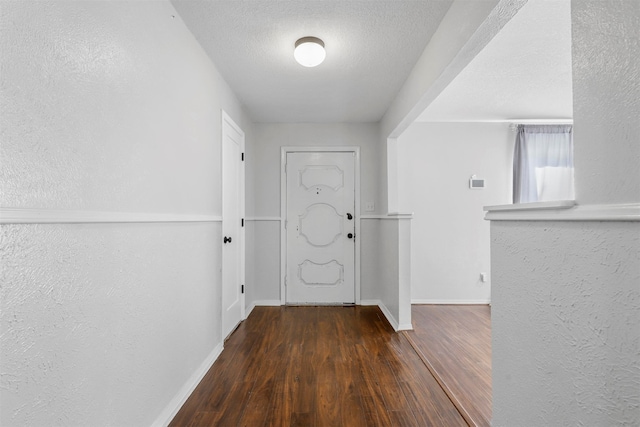 doorway with dark hardwood / wood-style flooring and a textured ceiling