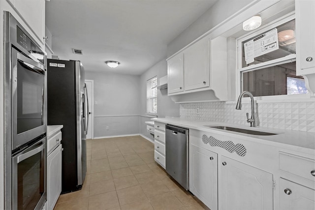 kitchen with white cabinets, backsplash, sink, and stainless steel appliances