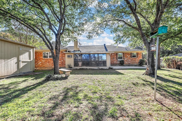 rear view of property featuring a yard and a storage unit