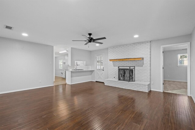 unfurnished living room with a fireplace, dark hardwood / wood-style flooring, and a healthy amount of sunlight