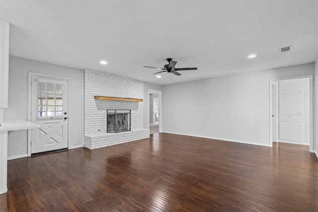 unfurnished living room featuring a fireplace, dark hardwood / wood-style flooring, and ceiling fan