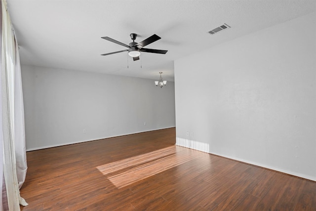 spare room featuring ceiling fan with notable chandelier, a textured ceiling, and dark hardwood / wood-style flooring