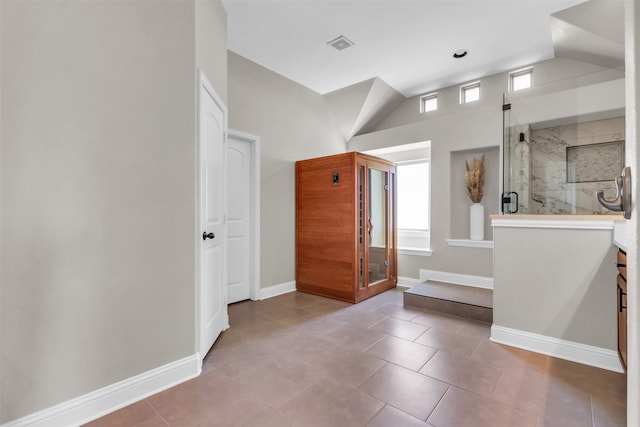 bathroom featuring tile patterned floors, a shower with door, and vaulted ceiling