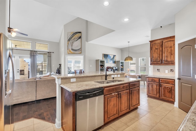 kitchen with pendant lighting, sink, light tile patterned floors, light stone counters, and stainless steel appliances