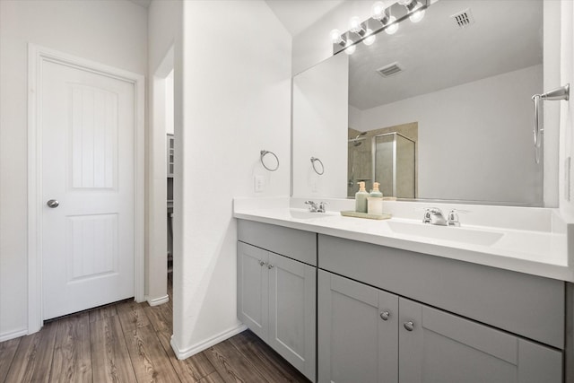 bathroom featuring a shower with shower door, hardwood / wood-style flooring, and vanity