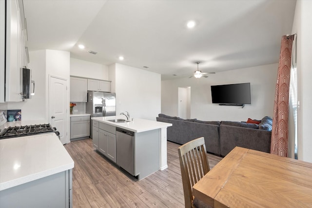 kitchen featuring gray cabinetry, appliances with stainless steel finishes, sink, and a kitchen island with sink