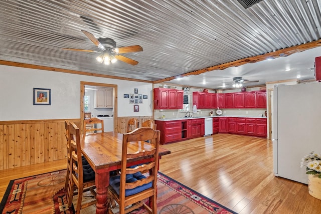 dining area featuring sink, wooden walls, washer and dryer, light wood-type flooring, and ornamental molding