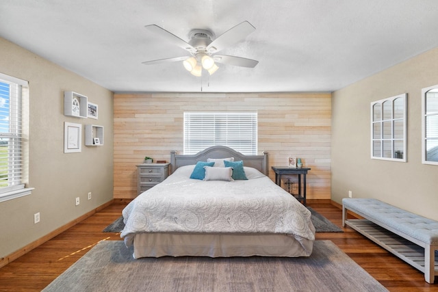 bedroom featuring hardwood / wood-style floors, ceiling fan, and wooden walls