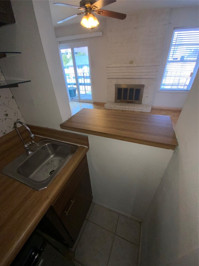 kitchen with wood counters, light tile patterned floors, ceiling fan, and sink