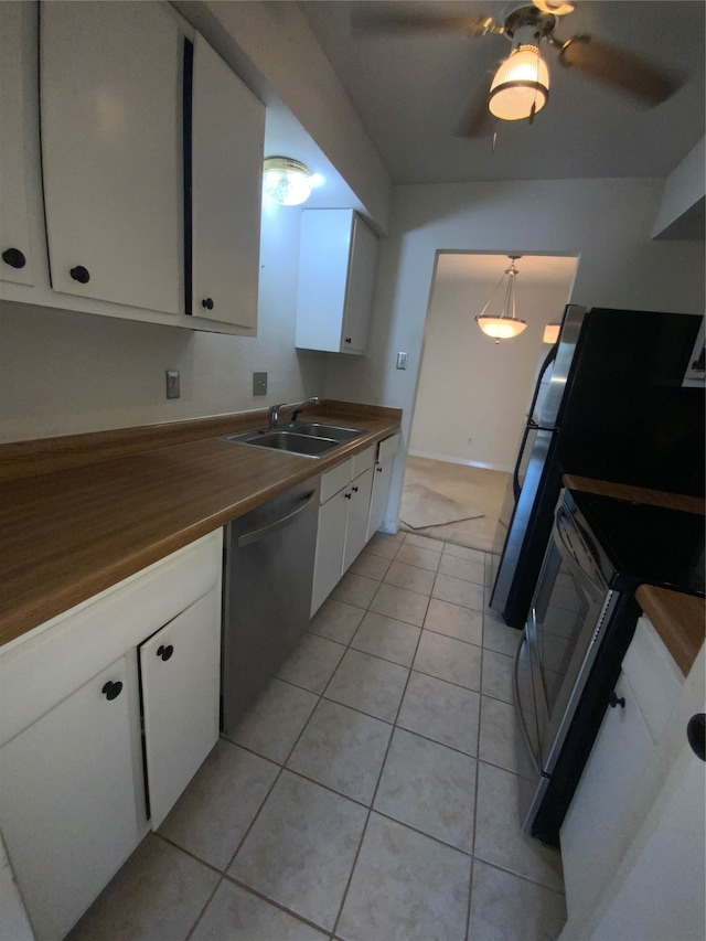 kitchen with stainless steel dishwasher, sink, decorative light fixtures, butcher block countertops, and white cabinetry