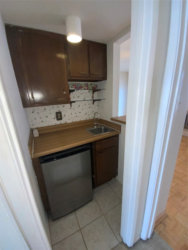 kitchen featuring dishwasher, light parquet flooring, dark brown cabinetry, and sink