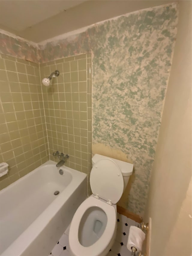 bathroom with tile patterned flooring, tiled shower / bath combo, and toilet