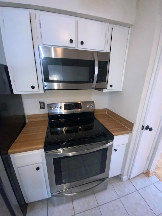 kitchen with white cabinets, light tile patterned flooring, and stainless steel appliances