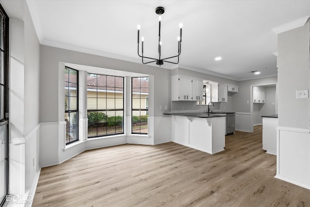 kitchen featuring a breakfast bar, crown molding, kitchen peninsula, light hardwood / wood-style floors, and white cabinetry