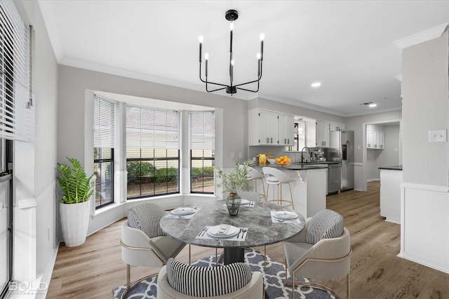 dining area featuring sink, light hardwood / wood-style floors, a notable chandelier, and ornamental molding