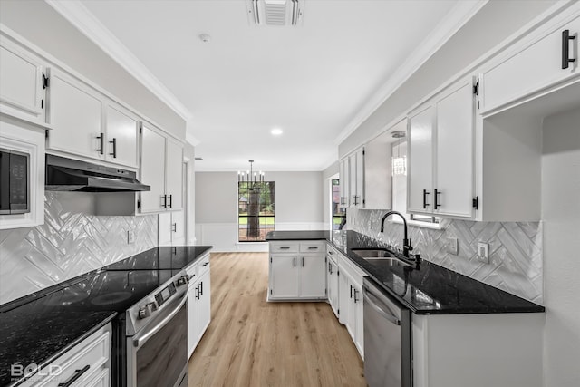 kitchen with hanging light fixtures, sink, dark stone countertops, appliances with stainless steel finishes, and white cabinetry