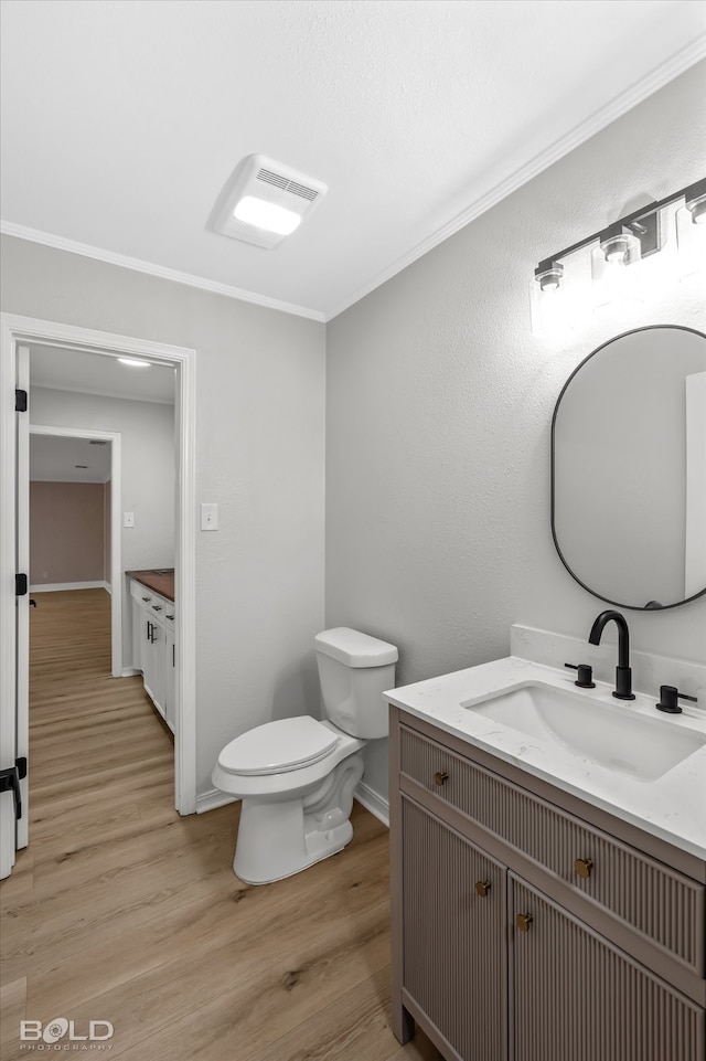 bathroom featuring ornamental molding, vanity, wood-type flooring, and toilet