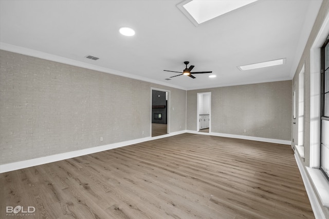 unfurnished room featuring hardwood / wood-style flooring, ceiling fan, crown molding, and a skylight