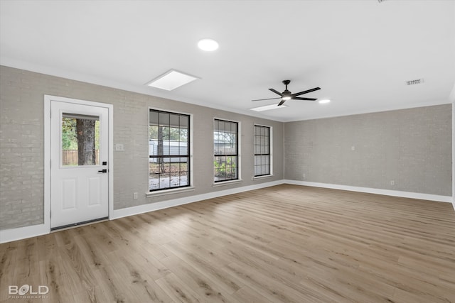 interior space featuring light hardwood / wood-style floors, ceiling fan, and brick wall