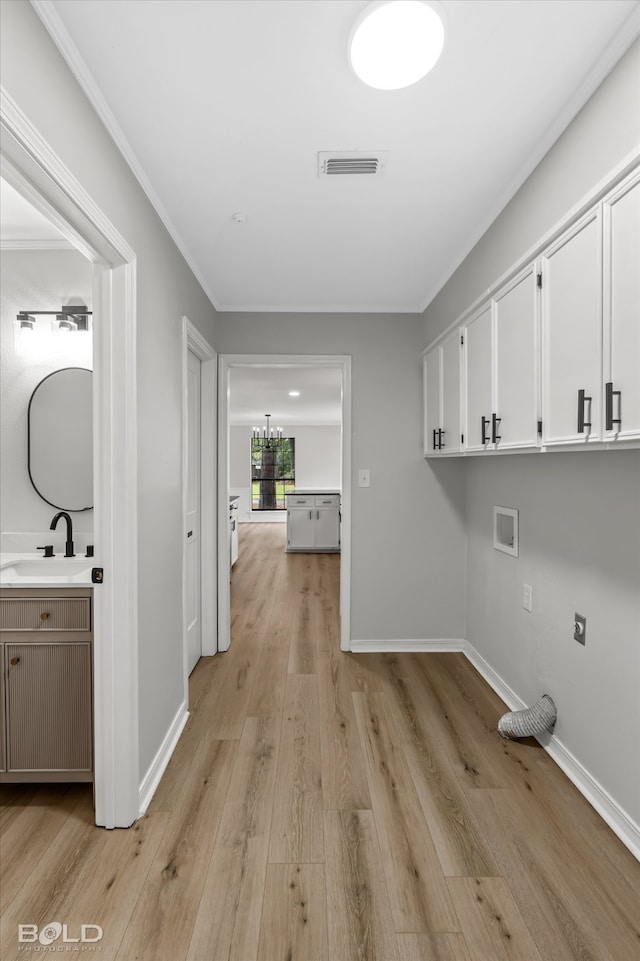 clothes washing area featuring cabinets, sink, hookup for a washing machine, light wood-type flooring, and ornamental molding