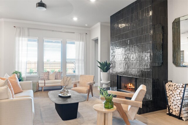 living room with a tile fireplace, hardwood / wood-style floors, and crown molding