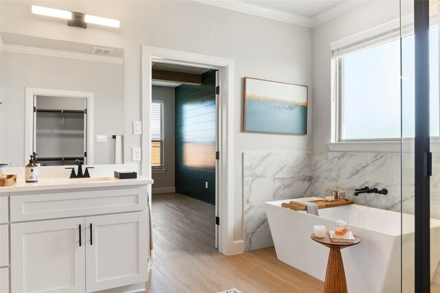 bathroom featuring vanity, crown molding, a bath, wood-type flooring, and tile walls