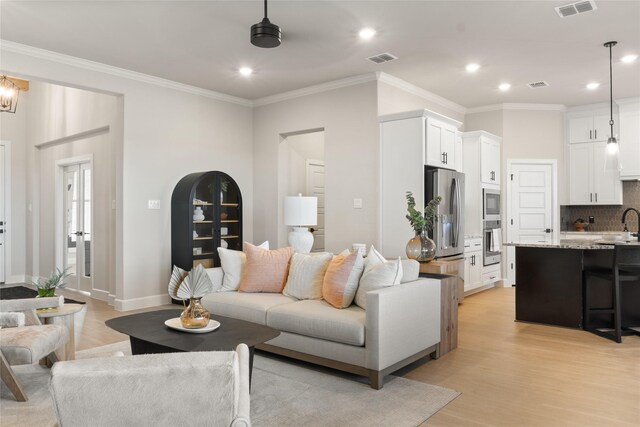 living room with light wood-type flooring and crown molding