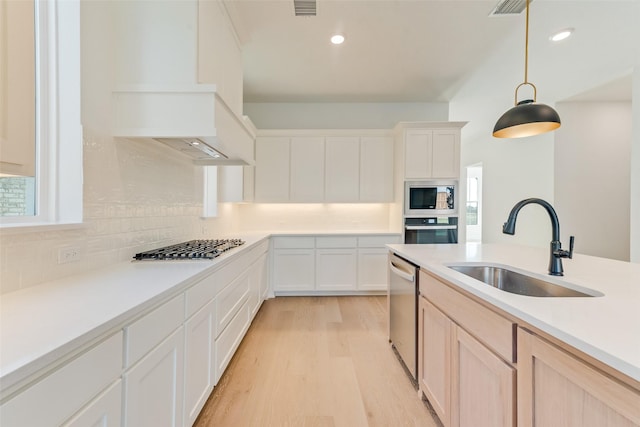 kitchen with white cabinetry, sink, hanging light fixtures, stainless steel appliances, and tasteful backsplash