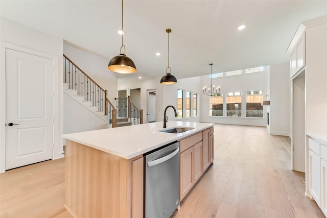 kitchen featuring dishwasher, light brown cabinets, a center island with sink, sink, and hanging light fixtures