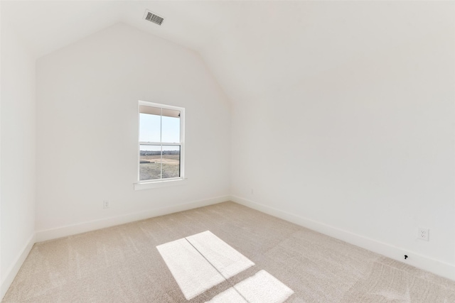 spare room featuring light colored carpet and vaulted ceiling