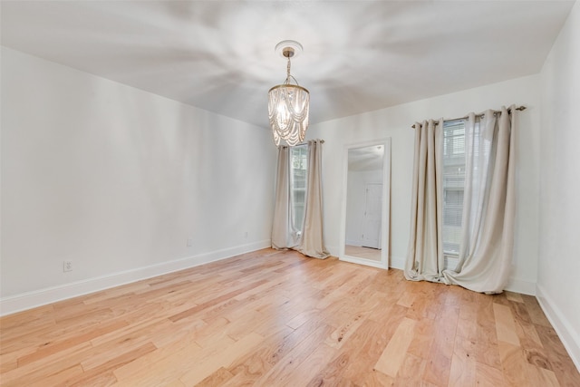 unfurnished room with wood-type flooring, an inviting chandelier, and a healthy amount of sunlight