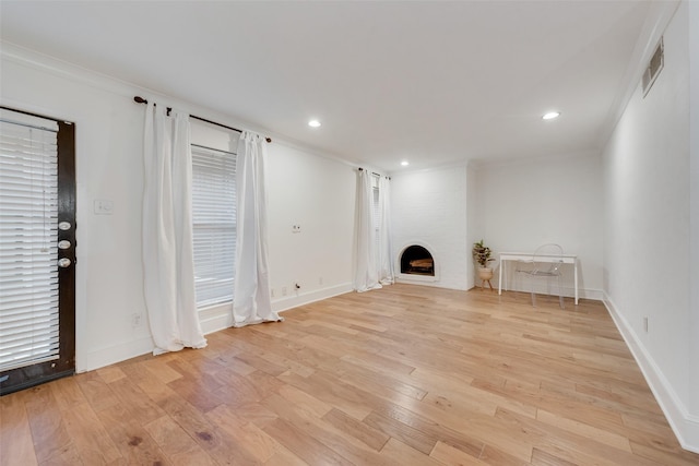 unfurnished living room featuring a fireplace, ornamental molding, and light hardwood / wood-style flooring