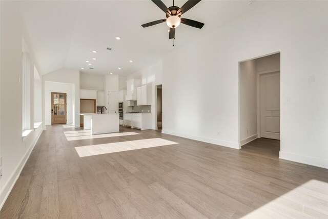 unfurnished living room featuring ceiling fan, light hardwood / wood-style floors, and vaulted ceiling