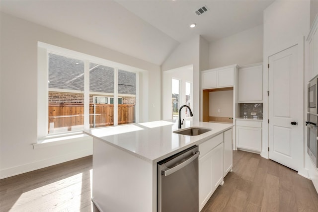 kitchen with dishwasher, a center island with sink, sink, vaulted ceiling, and white cabinetry