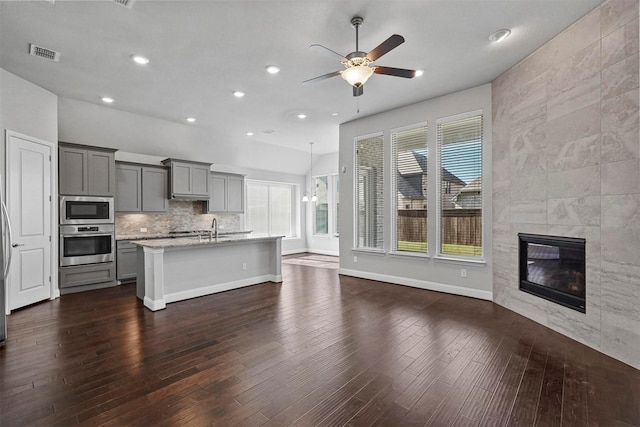 kitchen with visible vents, dark wood-style floors, appliances with stainless steel finishes, gray cabinetry, and a fireplace