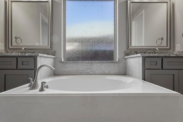 full bath with two vanities, plenty of natural light, and a garden tub