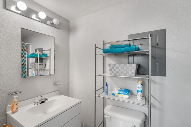 bathroom featuring vanity, a textured ceiling, and toilet