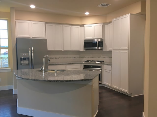 kitchen with stainless steel appliances, white cabinetry, a center island with sink, and sink