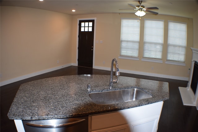 kitchen with dark stone counters, sink, stainless steel dishwasher, ceiling fan, and dark hardwood / wood-style flooring