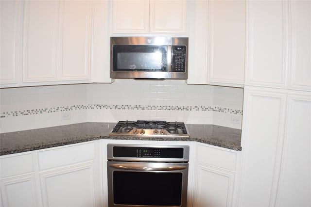 kitchen featuring white cabinets, appliances with stainless steel finishes, backsplash, and dark stone counters