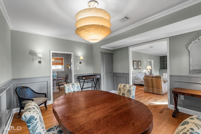 dining area with wood-type flooring and ornamental molding