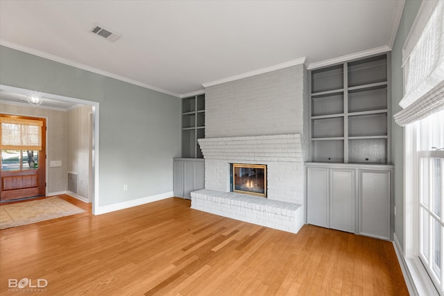 unfurnished living room with a fireplace, crown molding, hardwood / wood-style floors, and built in features