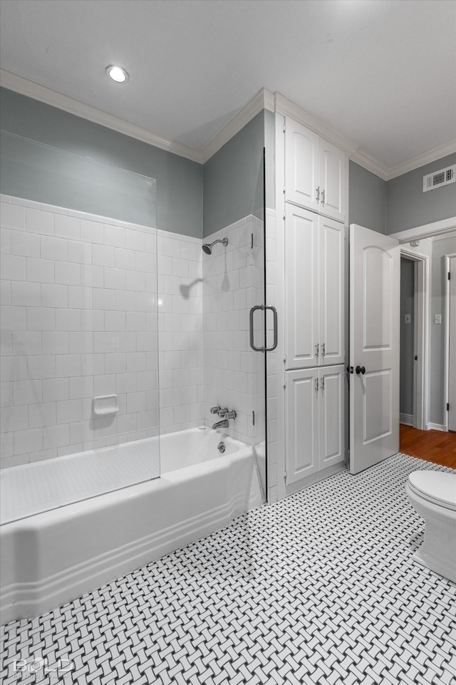 bathroom with tile patterned flooring, toilet, crown molding, and tiled shower / bath