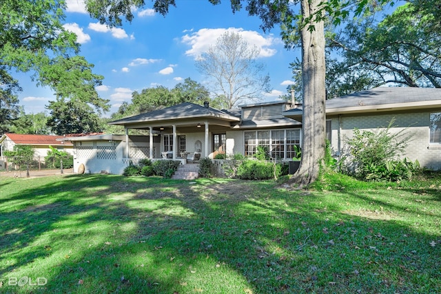 rear view of house featuring a lawn and a porch