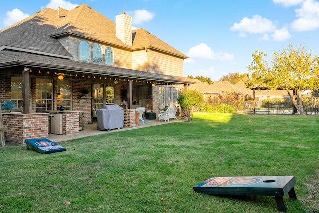 rear view of house featuring a lawn, an outdoor kitchen, and a patio area